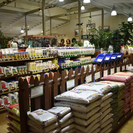 Indoor gardening section with shelves of plant care products and stacks of potting soil bags in a store.