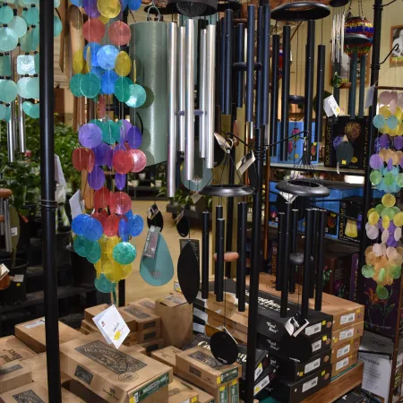 Colorful and metal wind chimes hanging in a store display with stacked boxes below them.