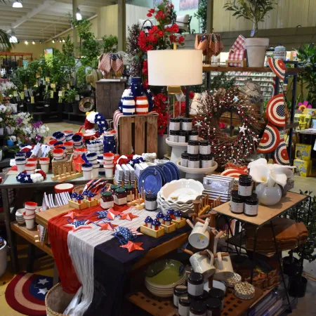 Store display with patriotic-themed kitchenware, home decor, and garden items in red, white, and blue colors.