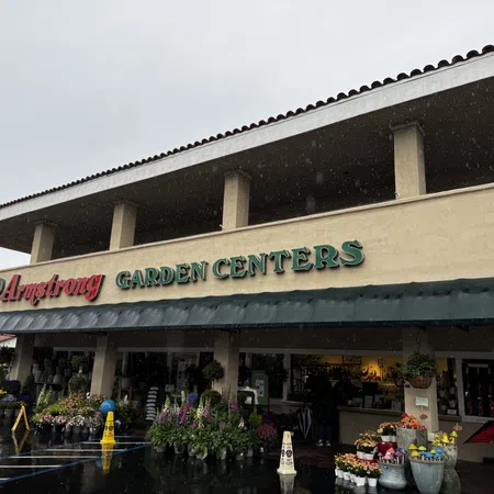 Exterior view of Armstrong Garden Centers with plants and flowers displayed outside on a rainy day.