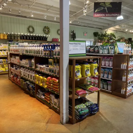Interior of a garden supply store aisle with shelves stocked with fertilizers, weed control, and garden products.