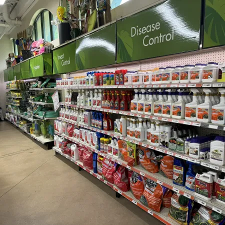 Aisle in a garden store displaying insect control and disease control gardening products on shelves.