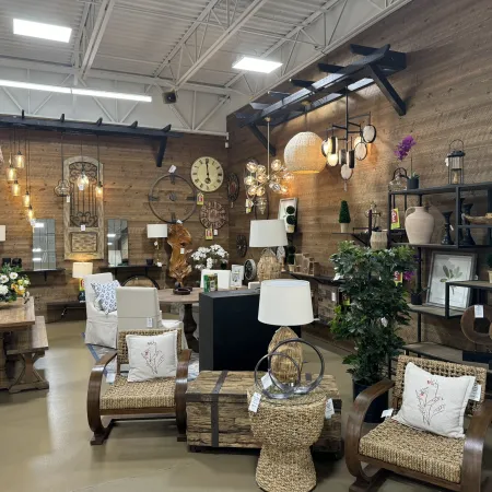 Rustic home decor store interior featuring wooden furniture, woven chairs, decorative clocks, and ambient lighting.
