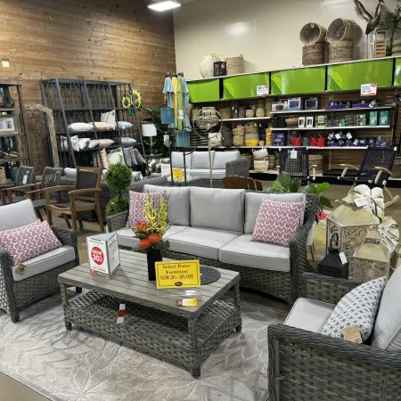 Indoor display of woven rattan patio furniture set with cushions and coffee table in a store showroom.
