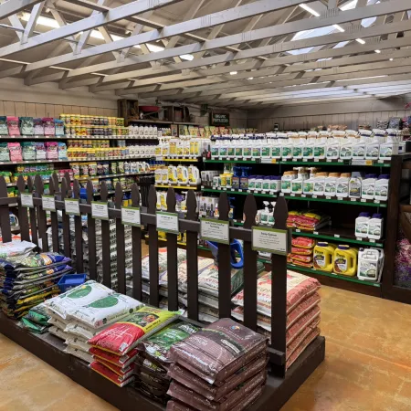 Garden supplies section with shelves of fertilizers, plant foods, and stacked soil bags under a wooden roof.