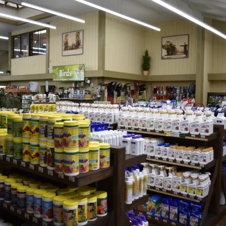 Indoor garden center shelves stocked with plant food, fertilizers, and gardening supplies under bright lights.