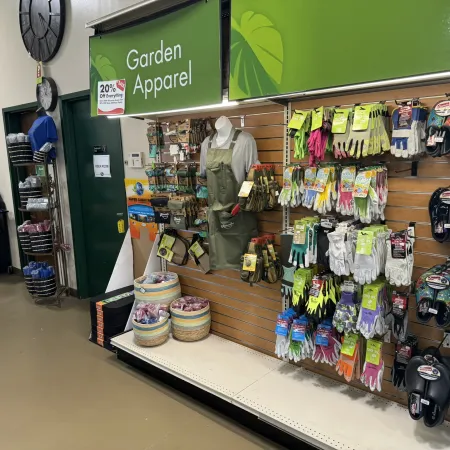 Garden Apparel section with gloves, aprons, and gardening accessories displayed on wooden slatwall inside a store.