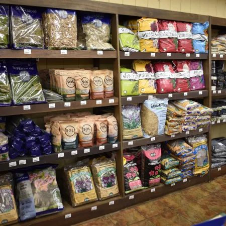 Store shelves stocked with various gardening and soil products including moss, fertilizer, mulch, and soil amendments.