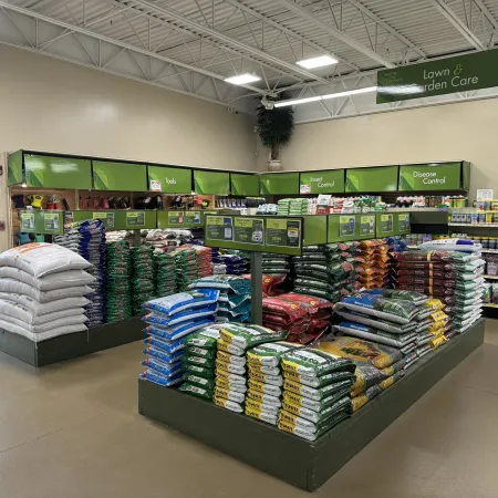 Lawn and garden care section with stacked bags of soil, fertilizer, and gardening products in a store.