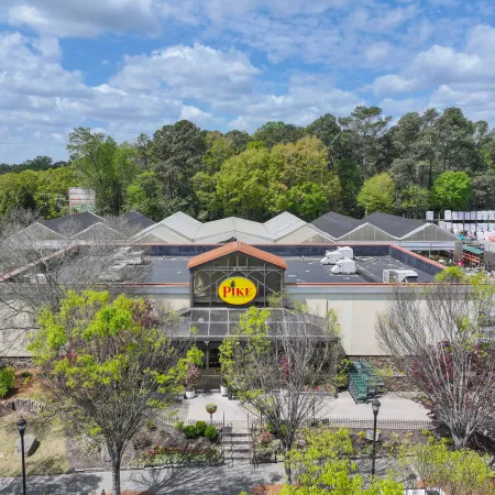 Pike Nursery building with outdoor plants and garden supplies surrounded by trees under a partly cloudy sky.