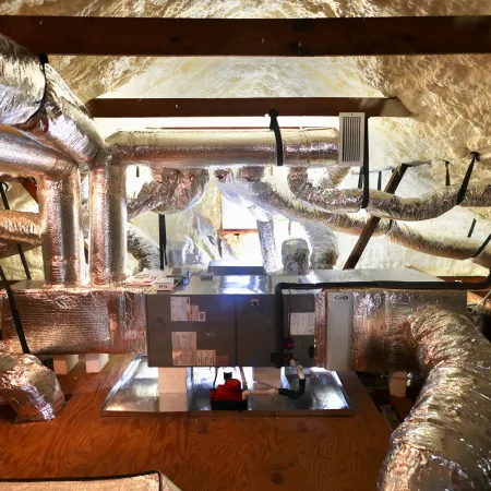 Insulated HVAC ductwork and furnace system installed in an attic with spray foam insulation.