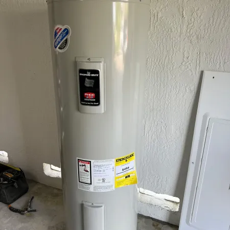 Tall white Bradford White water heater with informational and energy guide labels inside a utility room.