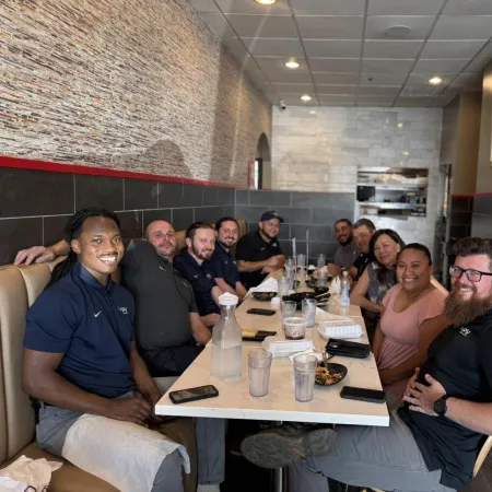 Group of diverse coworkers smiling and dining together in a casual restaurant setting with modern decor.