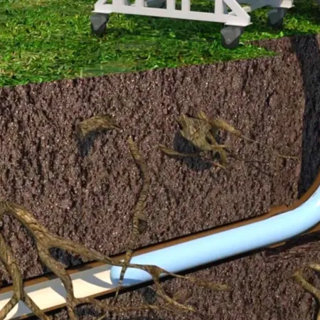 Cross-section of soil showing underground drainage pipes and roots beneath green grass surface.