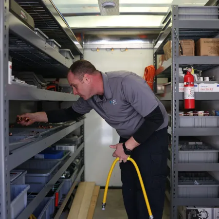 Technician organizing parts in a mobile service truck with shelves, tools, and equipment inside.