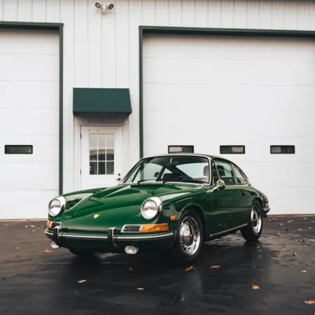 a green car parked in front of a garage