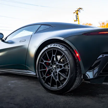 Matte black sports car with detailed rear wheel and sleek aerodynamic design parked outdoors.