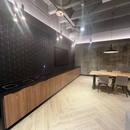 Modern office meeting room with wooden table, four chairs, pendant lighting, and geometric black wall design.