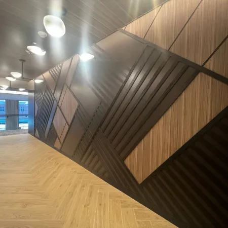 Modern hallway with artistic wooden wall panels in geometric patterns and light wood flooring under ceiling lights