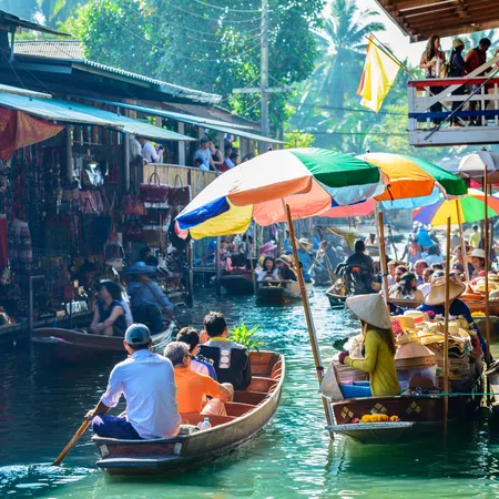 Colorful floating market with boats selling goods and tourists enjoying rides on a sunny day