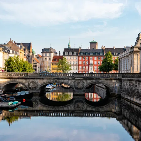 Historic stone bridge over canal with colorful buildings and boats in a European city on a clear day