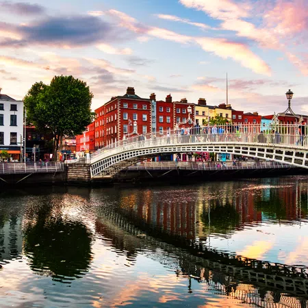 Colorful buildings and the Ha'penny Bridge reflected in Liffey River at sunset in Dublin, Ireland.