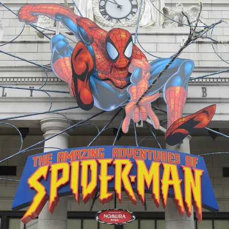 Spider-Man figure shooting web above a sign that reads The Amazing Adventures of Spider-Man on a building facade.