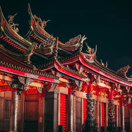 Night view of traditional Chinese temple with intricate red and gold architectural details and dragon decorations.