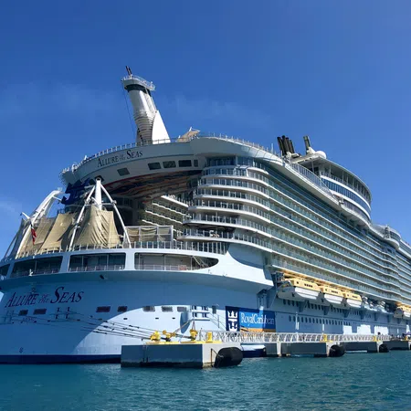 Large Allure of the Seas cruise ship docked at pier under clear blue sky over calm sea.
