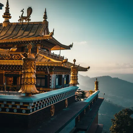 Golden roof details of a traditional temple overlooking scenic misty mountains at sunset.