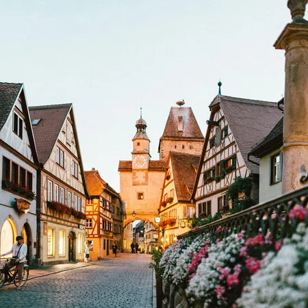 Cobblestone street with half-timbered houses and a historic clock tower in a charming European village.