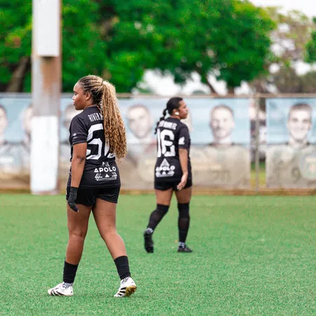 Women soccer players in black River Miami FC uniforms on a green field during a game or practice session.