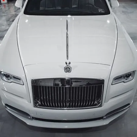 Front view of a luxury white Rolls-Royce car with iconic grille and Spirit of Ecstasy hood ornament.