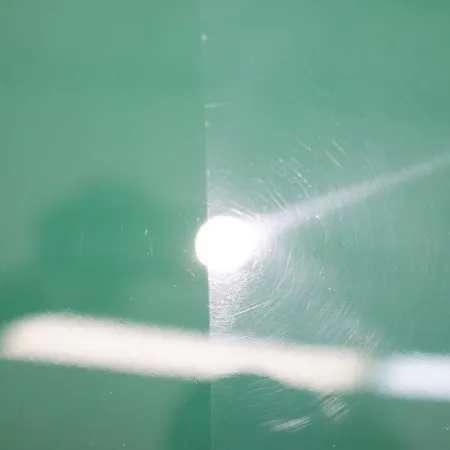 Green surface divided into polished and unpolished halves with light reflection and swirl marks visible.
