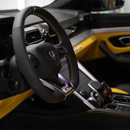 Luxury sports car interior with black and yellow leather, advanced dashboard, and multifunction steering wheel.