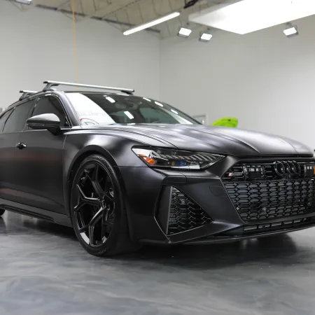 Matte black Audi sports car parked indoors with sleek design and black alloy wheels in showroom.