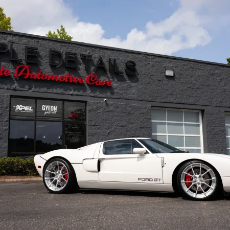 White Ford GT sports car parked in front of Simple Details Elite Automotive Care on a sunny day.