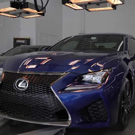 Sleek blue Lexus sports car with signature spindle grille parked indoors under bright ceiling lights