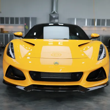 Front view of a yellow Lotus sports car inside a modern garage with polished concrete floor.