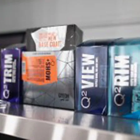 Close-up of Q2 Trim and Q2 View film packaging displayed on a metallic surface in a workshop.