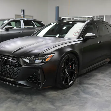Matte black Audi RS6 Avant parked in a modern garage with sleek design and black alloy wheels.