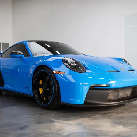 Blue Porsche sports car with black rims and yellow brake calipers in a showroom.