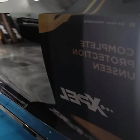 Glossy black car side panel reflecting an indoor environment with a visible decal text.