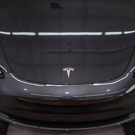 Front view of a sleek black Tesla electric car with distinctive logo on the hood in a showroom.