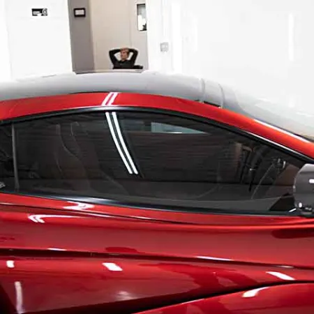 Sleek red sports car with tinted windows and glossy finish in a bright showroom environment.