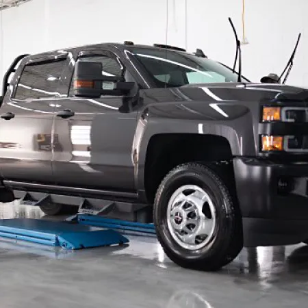 Dark gray heavy-duty pickup truck parked on a hydraulic lift in a clean indoor garage.
