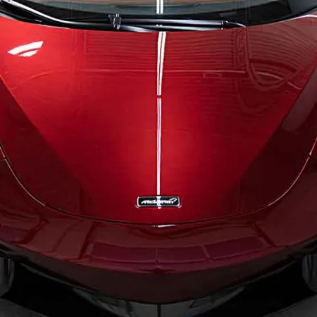 Front view of a shiny red McLaren sports car with sleek headlights and aerodynamic design.