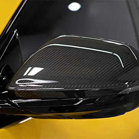 Close-up of a yellow car's carbon fiber side mirror with sleek aerodynamic design and glossy finish