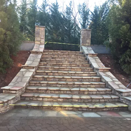 Stone staircase with decorative walls on sides, surrounded by trees and caution tape blocking access.