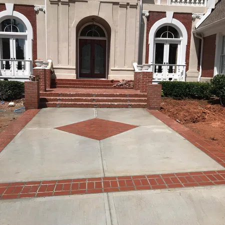 Front view of a house with a brick and concrete driveway featuring a diamond brick pattern in the center.